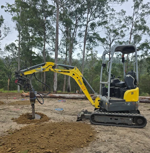 Top Shelf Earth Works mini excavator with auger attachment drilling post holes